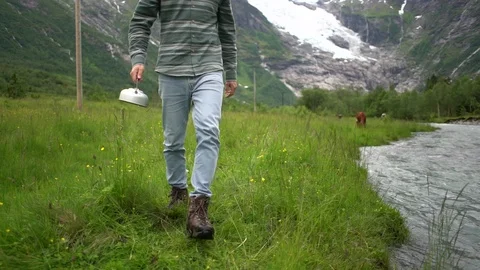 Handheld shot of a man walking towards the river to fill the water Video stock 114882076