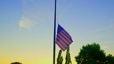 Handheld shot of a medium size USA flag flying at half mast on a beautiful b Stock Footage 202105861