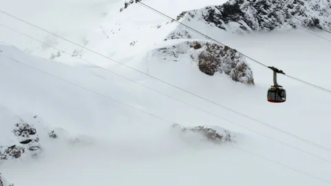 Handheld shot of modern cabin on cable railway going up snowy mountains Stock Footage 129091067