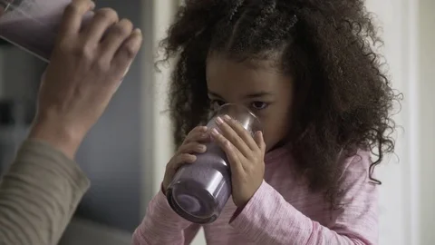 Handheld shot of mother and daughter drinking fresh berry smoothies in kitchen Stock Footage