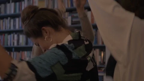 Handheld shot of multiracial friends dancing against window in library Stock Footage 114842869