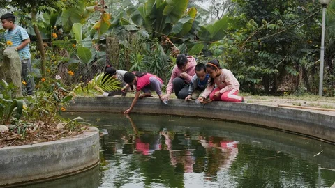 Handheld shot of native vietnamese children sitting by edge of fountain, hanoi Stock Footage 147369366