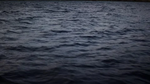 Handheld shot of ocean waves moving past a ship under cloudy sky, textured dark Stock Footage 328797396