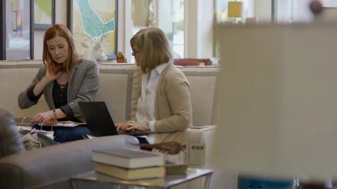 Handheld shot of owner using laptop computer while coworker arranging fabrics in Stock Footage