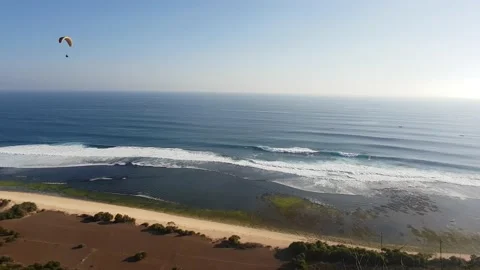 Handheld shot of a paraglider flying over waves breaking in Indian ocean Stock Footage 146349916