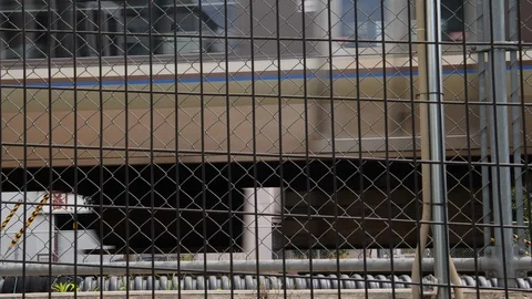 Handheld shot of passing train through chain fence with buildings in back, Japan Stock-Footage 146138462