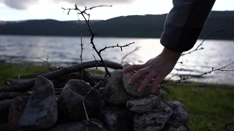 Handheld shot of a person building stack of stones to complete cairn Stock Footage 114882469