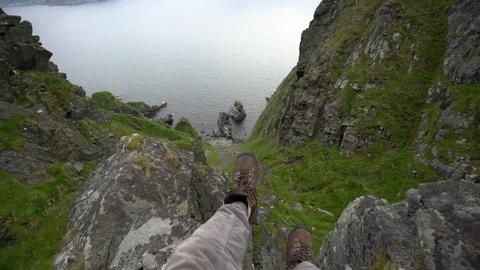 Handheld shot of a person flapping legs while sitting on the mountain rock Vídeo Stock 114882409
