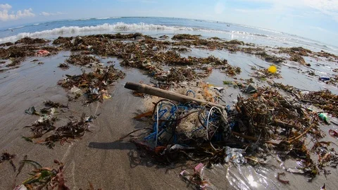 Handheld shot of plastic garbage on polluted beach near sea on sunny day, Bali Stock Footage 140291018