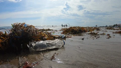 Handheld shot of plastic garbage on polluted sea shore, people in back, Bali Stock-Footage 140291325