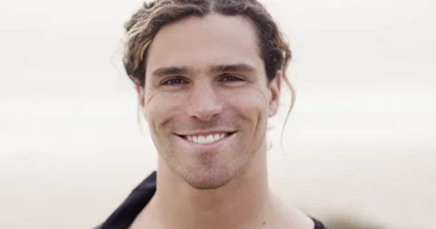 Handheld shot of pro surfer Alex Botelho looking into camera and smiling Stock Footage 158700811