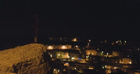 Handheld shot of pro surfer Bruno Valente standing on cliff and looking at city Stock Footage 158716475