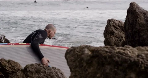 Handheld shot of pro surfer David Langer entering ocean water with surfboard Stock Footage 158064740
