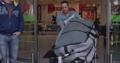 Handheld shot of pro surfer Eric Akiskalian walking with his luggage at airport 스톡 동영상 158648722