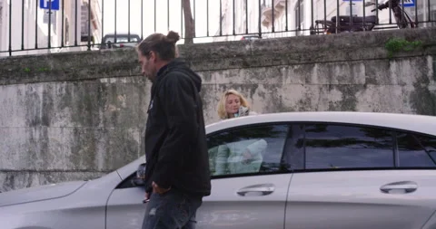 Handheld shot of pro surfer Hugo Vau and Ines Vau walking out of car on street Stock Footage 155014481
