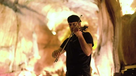 Handheld shot of pro surfer Nuno Santos playing violin in front of light up wall Stock Footage 155256700