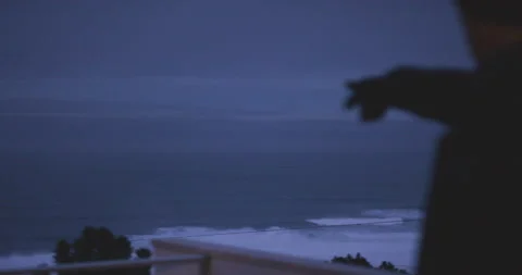 Handheld shot of pro surfer pointing towards broad ocean water at night Stock Footage 163277787