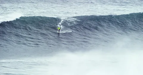 Handheld shot of pro surfer strapped behind jet ski wake surfing across ocean Video stock 163313773