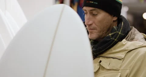 Handheld shot of professional surfer David Langer looking at new surfing board Stock Footage 158066856