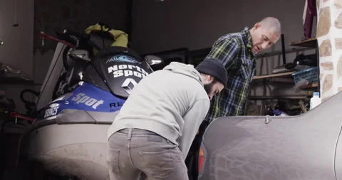 Handheld shot of professional surfer David Langer pulling jet ski out of garage Stock Footage 160542874
