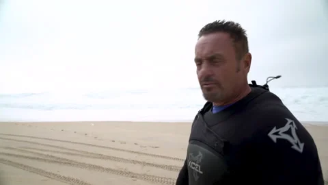 Handheld shot of professional surfer Eric Akiskalian talking about size of waves Stock Footage 151834613