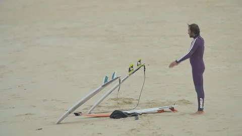 Handheld shot of professional surfer Kohl Christensen stretching on sandy beach Stock Footage 158651903