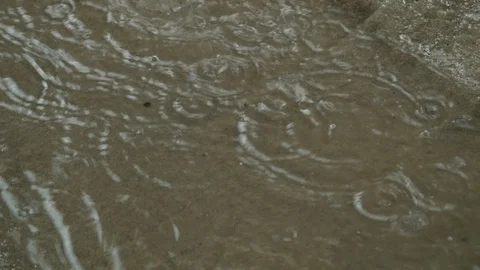 Handheld shot of raindrops falling on ground, creating puddle of water, Cuba Stock Footage 141661987
