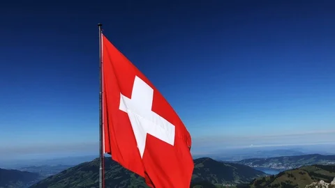 Handheld shot of red and white Swiss Flag fluttering against blue sky Stock Footage 120428019
