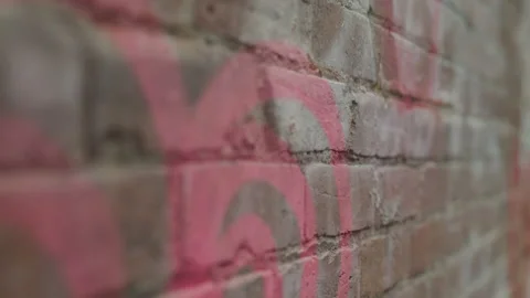 Handheld shot of red graffiti on brick wall street during cloudy day Stock Footage 208743156