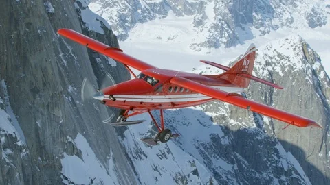 Handheld shot of red plane flying above rocky mountains, Tordrillo Mountain Stock Footage 129129000
