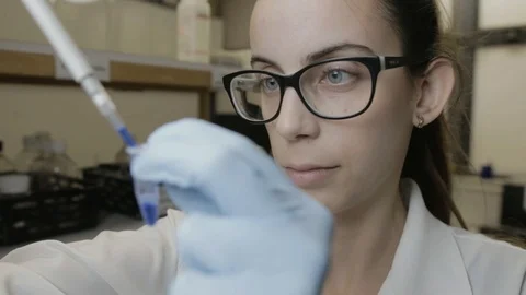 A handheld shot of a researcher pipetting samples to smaller vials in a genetic  Stock Footage 97754640