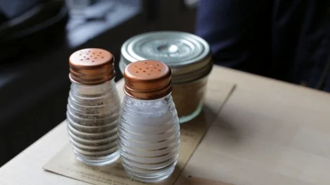A handheld shot of salt and pepper shakers on a restaurant table Stock Footage 87857107