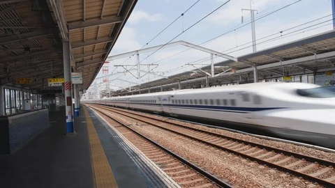 Handheld shot of shinkansen passing through train station on sunny day, Japan Stock Footage 146145587
