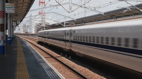 Handheld shot of shinkansen passing through train station on sunny day, Japan Vídeos de archivo 146145650
