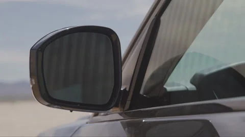Handheld shot of side mirror of dark car parked outdoors during sunny day Vídeos de archivo 208757360