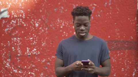Handheld shot of smiling man talking on phone against red wall Stock Footage 120428882