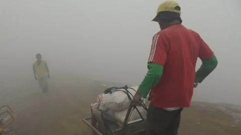 Handheld shot of sulfur mine worker in grey toxic smoke Indonesia Asia 스톡 동영상 78440761