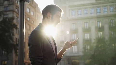 Handheld shot of sunlight streaming through businessman using smart phone Stock Footage 77769570