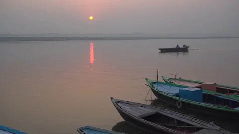 A handheld shot of a sunset over river Ganga - boat passing through the shot Stock Footage 114659843