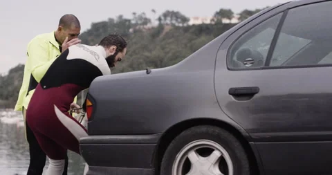 Handheld shot of surfer David Langer helping up jet ski out of water with car Stock Footage 160536604