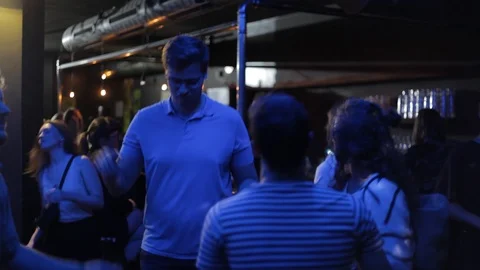 Handheld shot of tall man dances with friends on dance floor Video stock 114847925