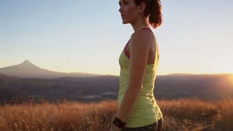 Handheld shot of thoughtful woman standing against mountains during sunset Stock Footage