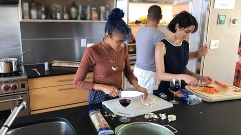 Handheld shot of three friends preparing meal in the kitchen 스톡 동영상 115060315
