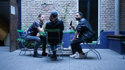 Handheld shot of three men sitting outside of club Stock-Footage 115090154
