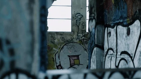 Handheld shot through broken wall inside an abandoned warehouse Stock Footage 112896340