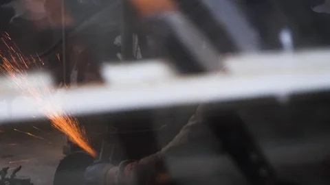 Handheld shot through glass window of man sharpening steel blade in hanoi Stock Footage 147370959