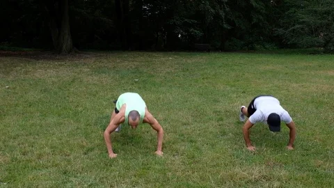 Handheld shot of two active young men doing warm-up exercise together in park Video stock 120435923