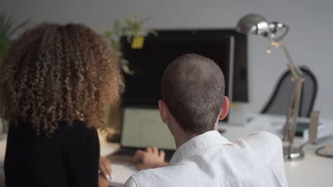 Handheld shot of two executives discussing over laptop Stock Footage 114877857