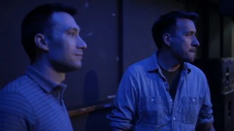 Handheld shot of two men chat and drink in rear of nightclub Stock Footage 114847897