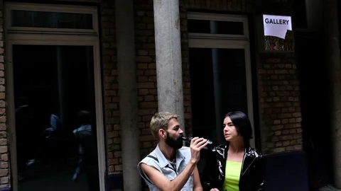 Handheld shot of two people talking and sipping outside a building Stock Footage 114886104